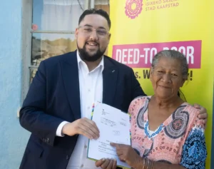 Councillor Carl Pophaim with the title deed recipient from Bishop Lavis