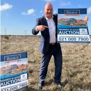 Alderman James Vos showing the poster of property auction in Cape Town