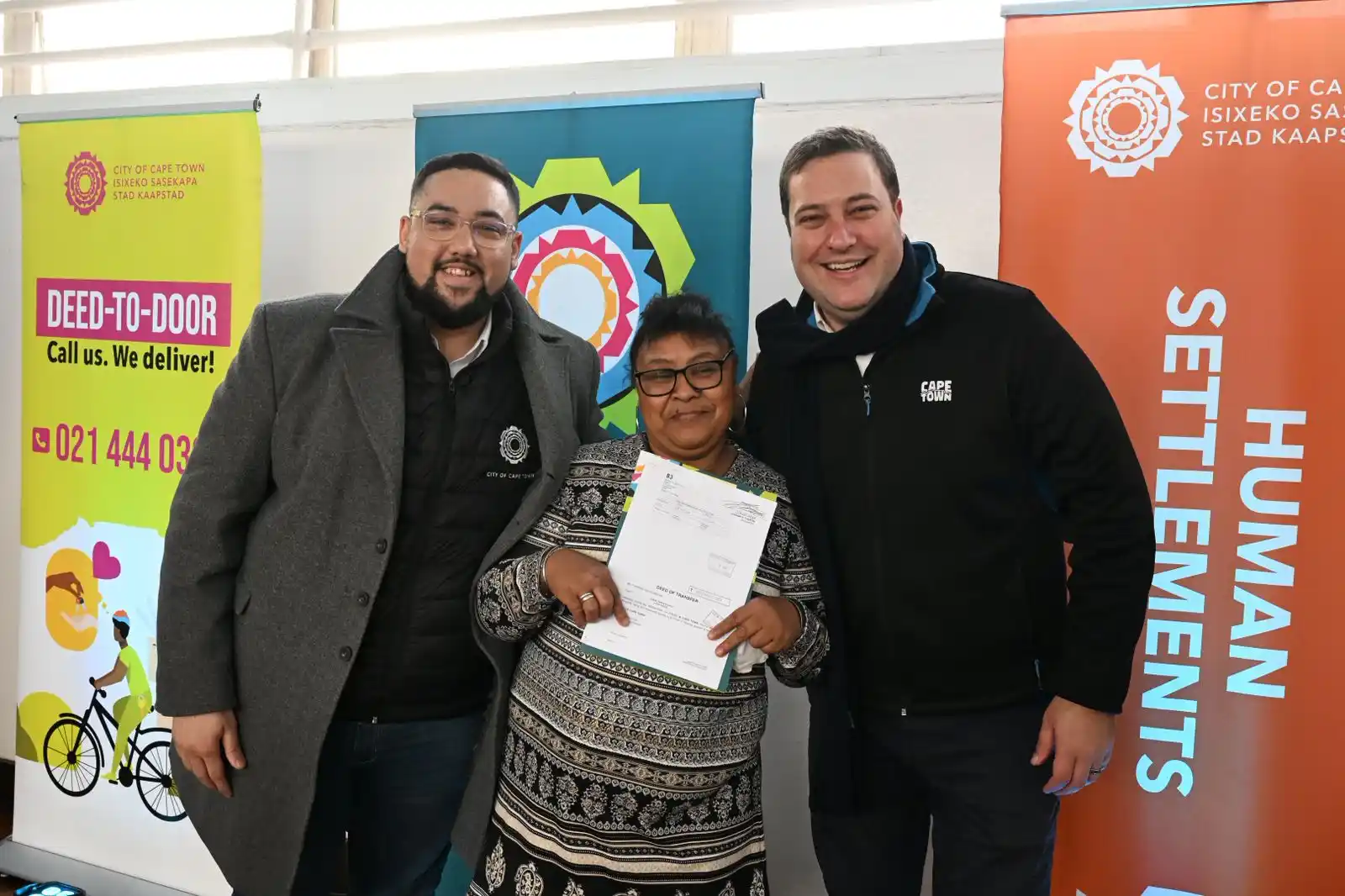 Mayor Geordin Hill-Lewis and Councillor Carl Pophaim with the title deed recipient of the Kensington resident in Cape Town