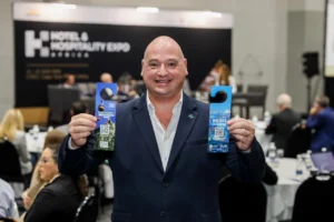 Alderman James Vos posing with newly launched Door Hangers at Hotel and Hospitality Expo Africa, Cape Town